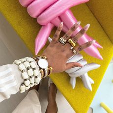 a hand is pictured with many rings and some bracelets and bangles on