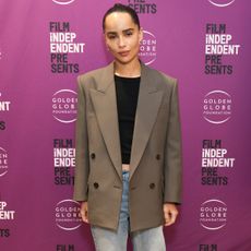 Zoe Kravitz wears a tan blazer with jeans, and a black top.