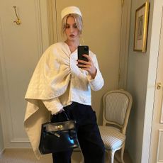 fashion influencer @christietyler wearing a white pillbox hat and Esant cape jacket